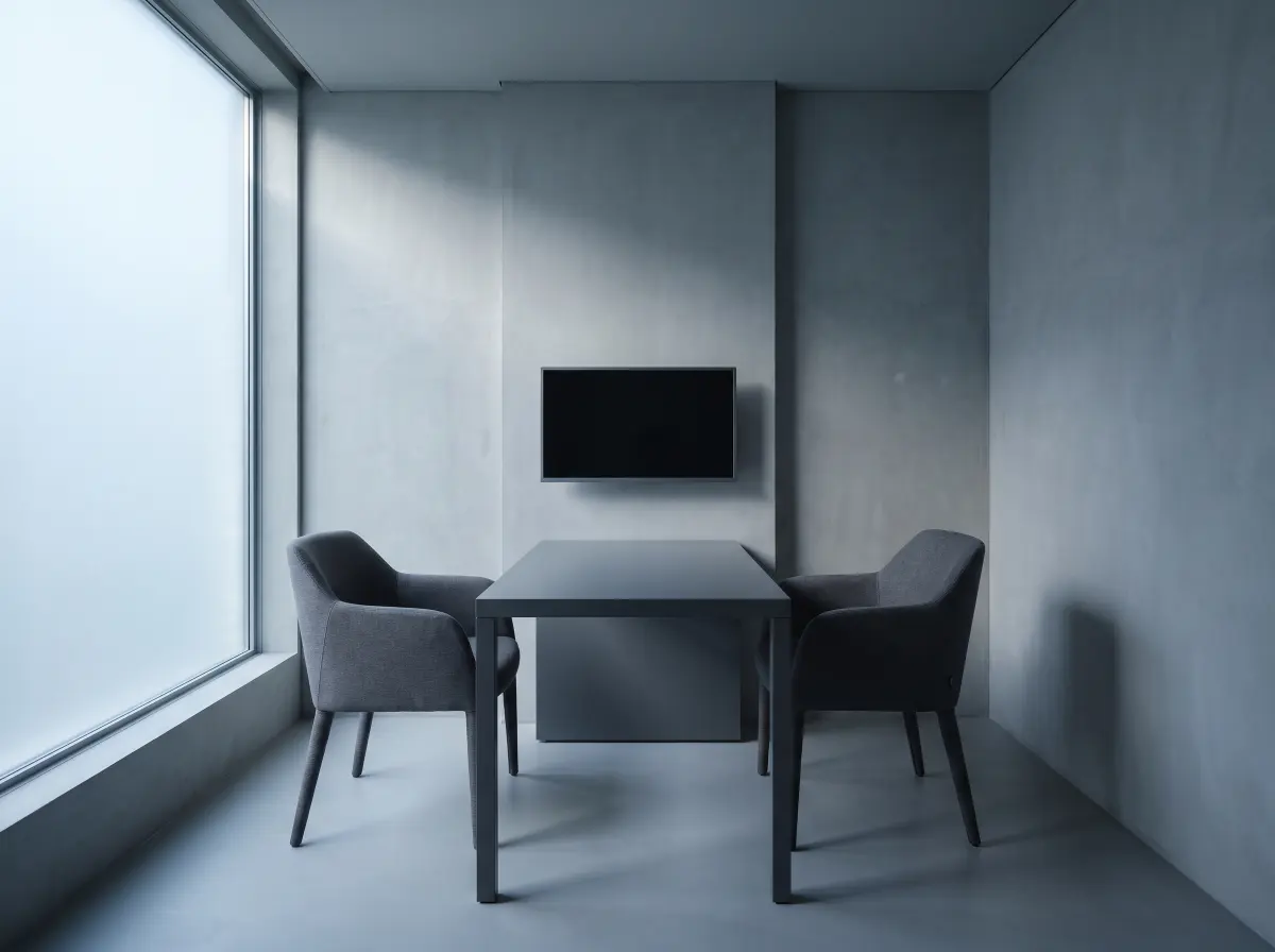 A small private consultation room with a plain desk and two chairs facing each other.
